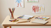Children's art supplies arranged on a classroom table